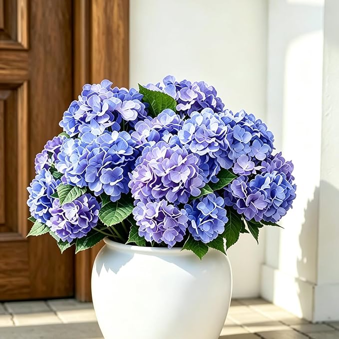 Purple artificial hydrangea stems arranged in a large outdoor planter, UV resistant faux flowers
