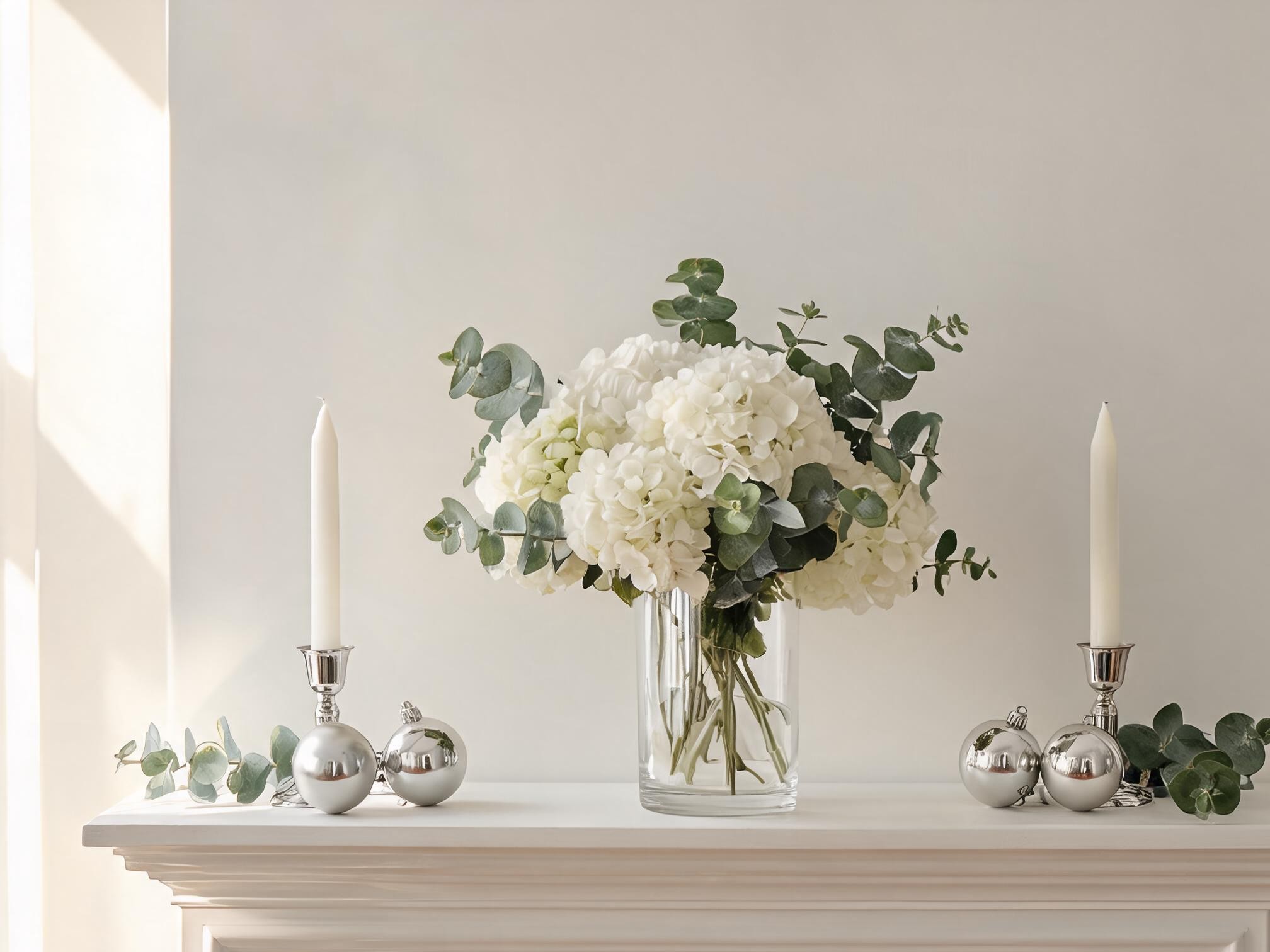 white artificial hydrangea arrangement styled with silver candlesticks and ornaments on a mantelpiece for Christmas