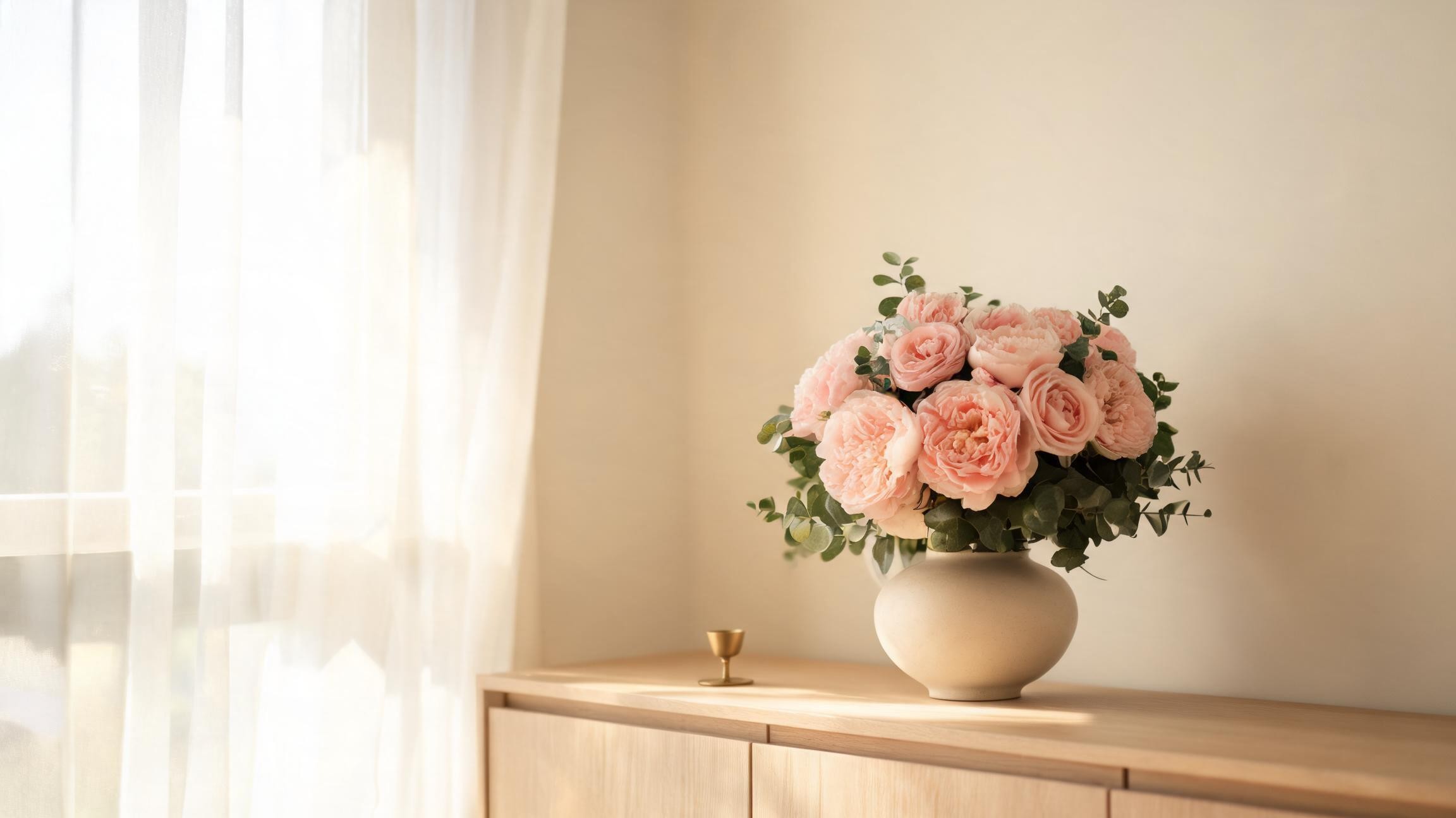 artificial silk flower arrangement in a cream vase on a wooden sideboard